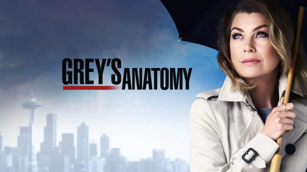 Meredith Grey, a blonde woman holds an umbrella