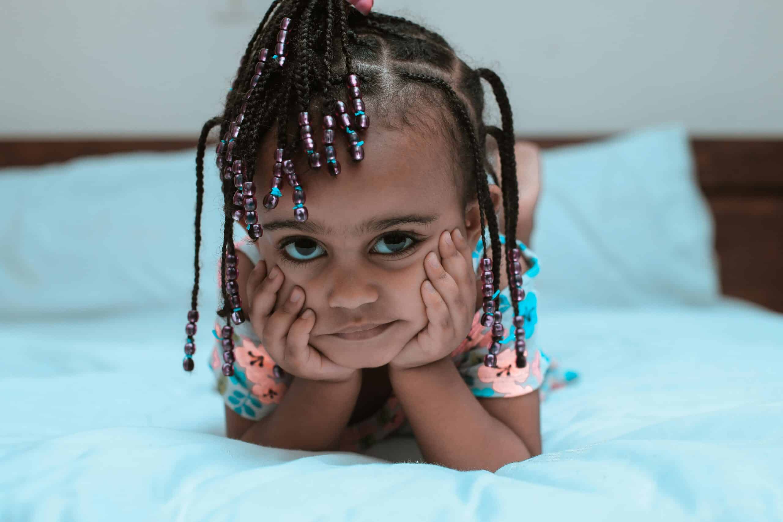 Little girl looking at the camera with a braided and beaded hairstyle.