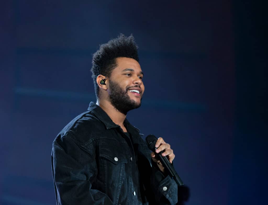 The Weeknd onstage, holding a microphone.