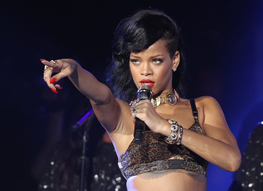 Rihanna pointing while singing into a microphone.