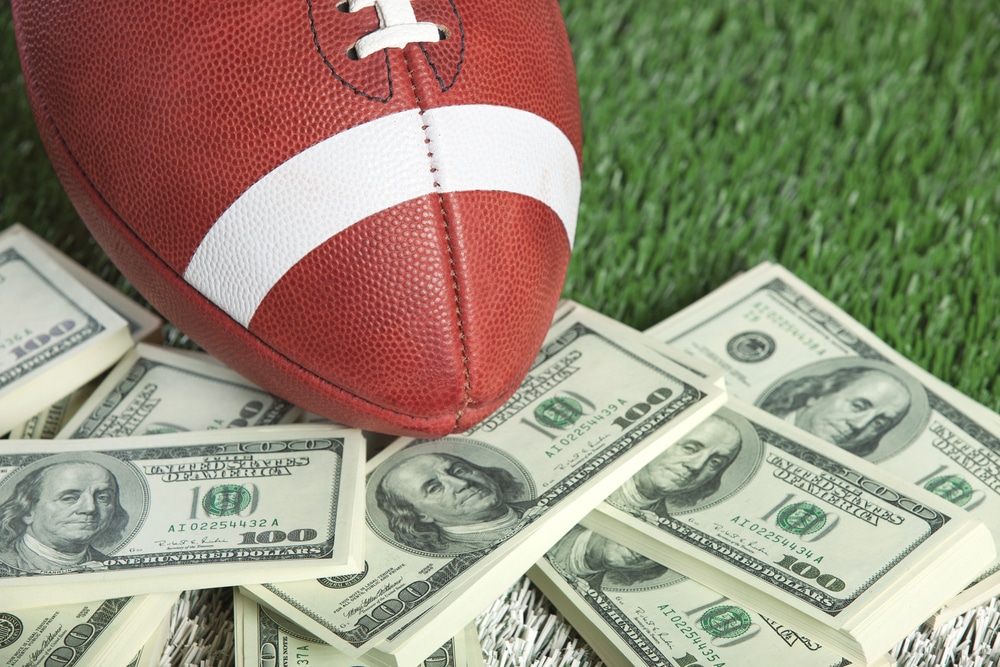 Football on top of a pile of money on turf