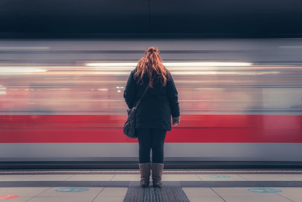 A woman watching a subway train pass by rapidly.