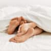 couple's feet cuddling in bed