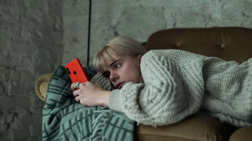 teenage girl scrolling on her phone while laying down