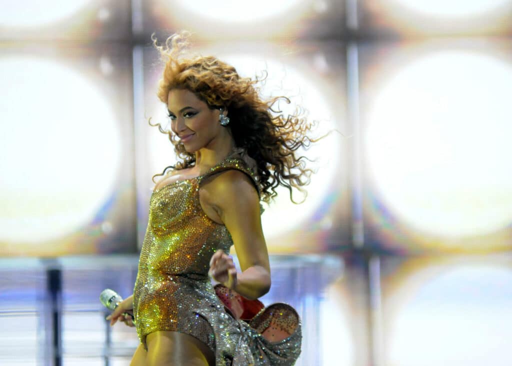 Beyonce performing at a concert in a gold dress.