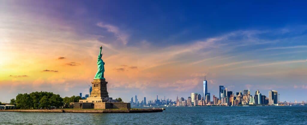 A skyline of New York City life during sunrise with the Statue of Liberty.