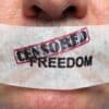 Man with mouth taped over with 'censored freedom' written.