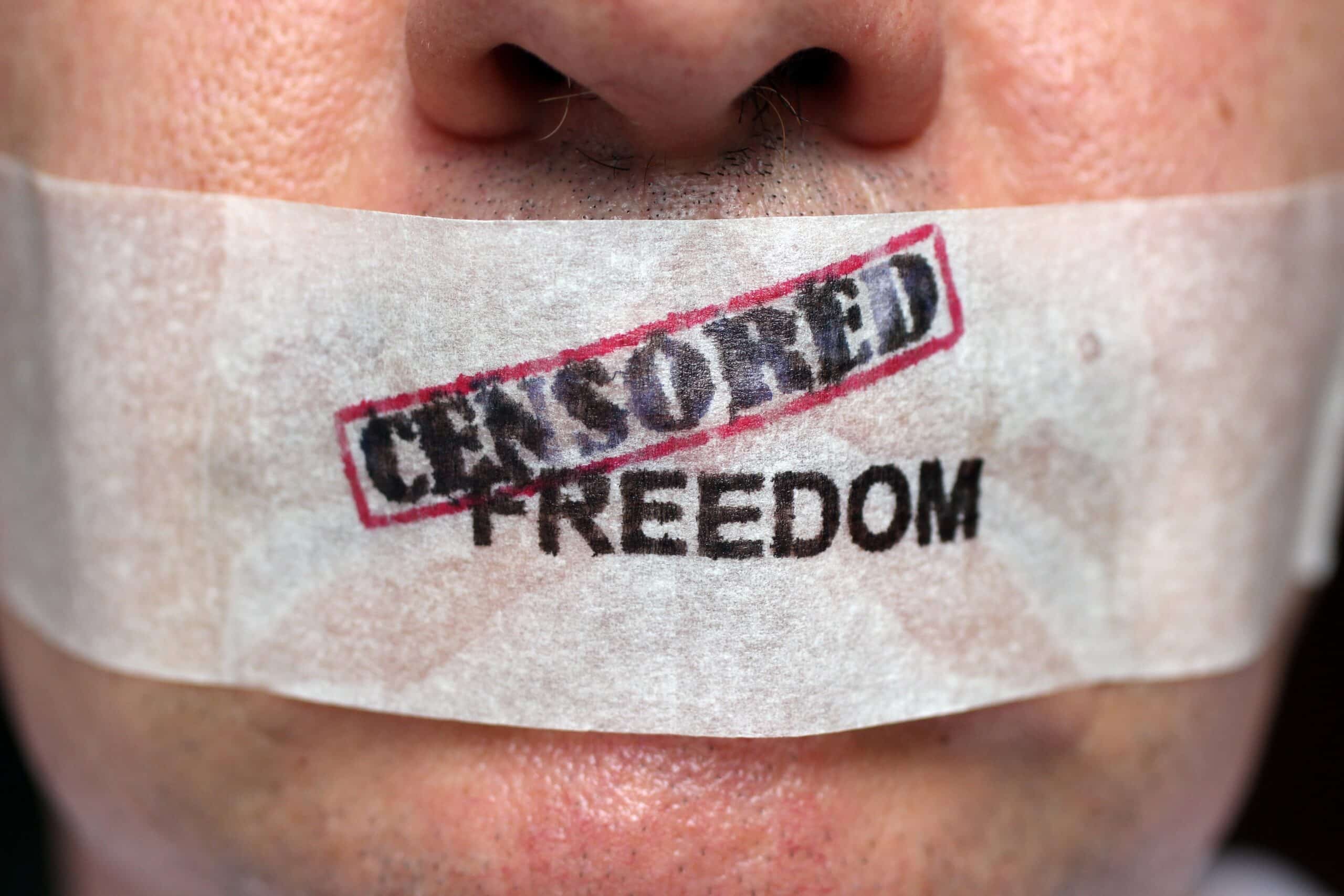 Man with mouth taped over with 'censored freedom' written.