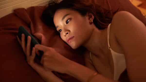 young woman scrolling on phone in bed