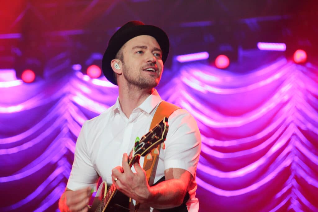 Justin Timberlake playing a guitar while on stage.