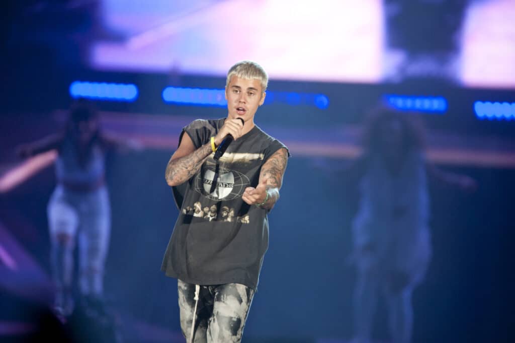 Justin Bieber singing into a microphone wearing a Wu-Tang Clan shirt.