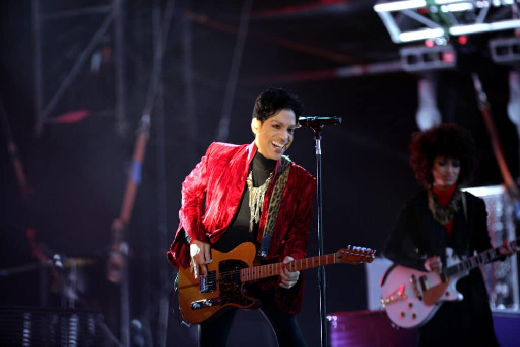 Prince playing a guitar on stage.