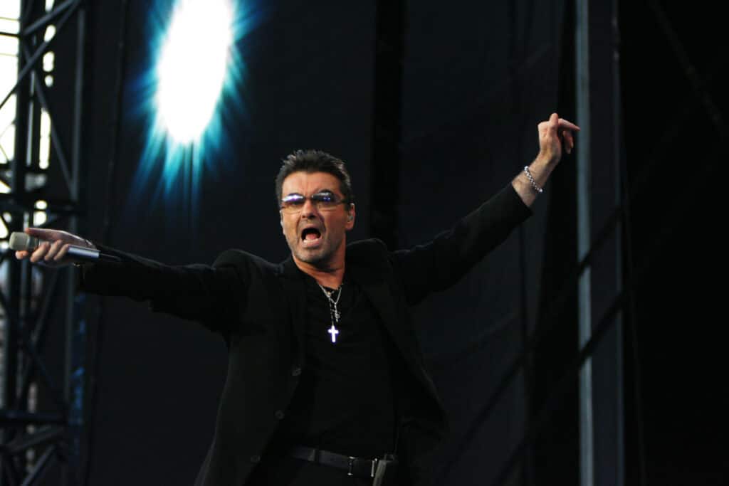 George Michael standing on stage holding a microphone.
