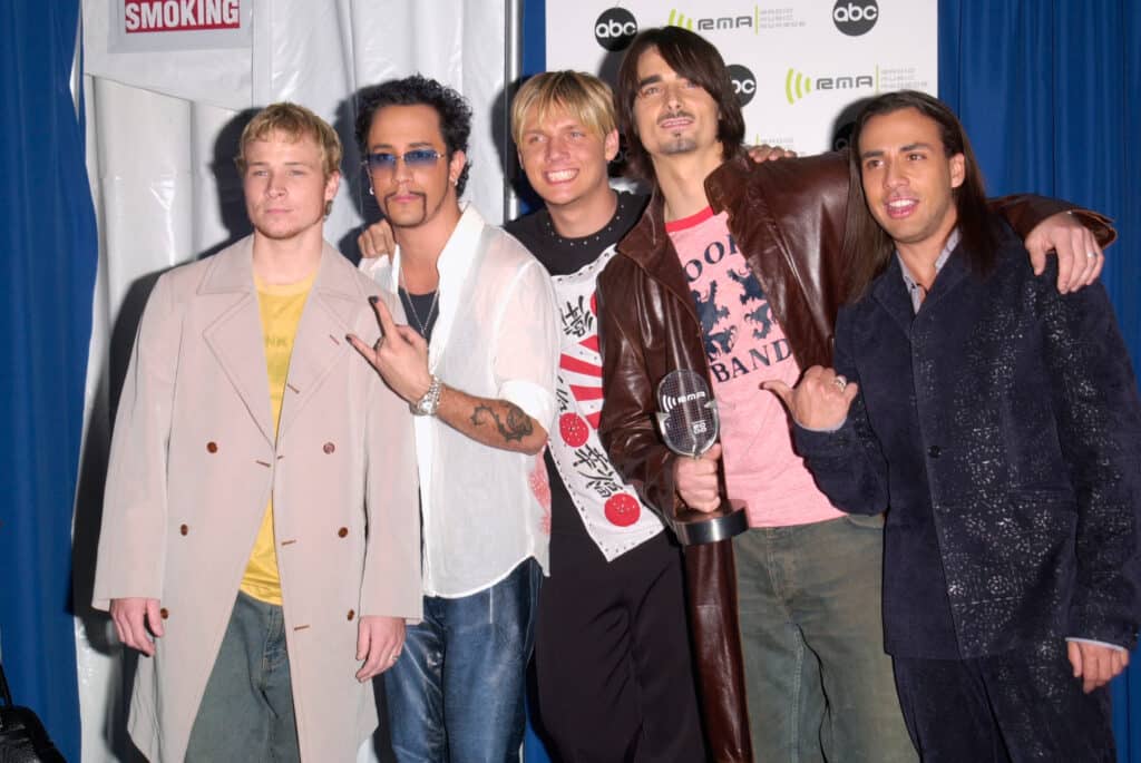 (From left to right) Brian Littrell, AJ McLean, Nick Carter, Kevin Richardson, and Howie Dorough posing for a group photo on a red carpet.