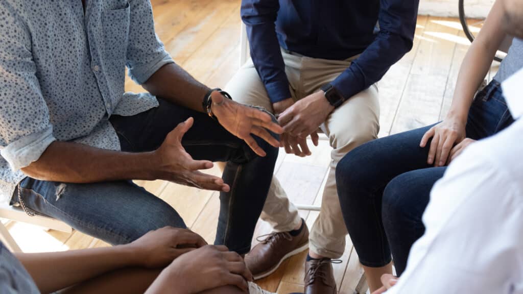 Laps of men sitting in a circle as part of a support group.