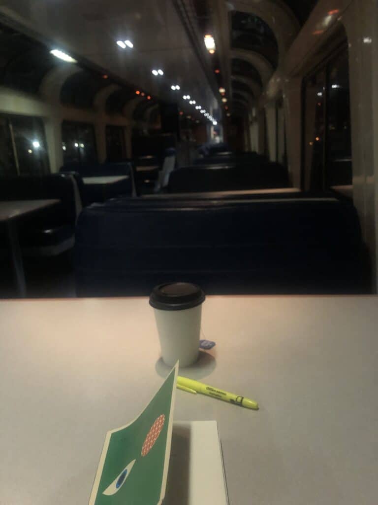 Panorama car at night, dark, empty. A book, pen, cup of tea on the table.