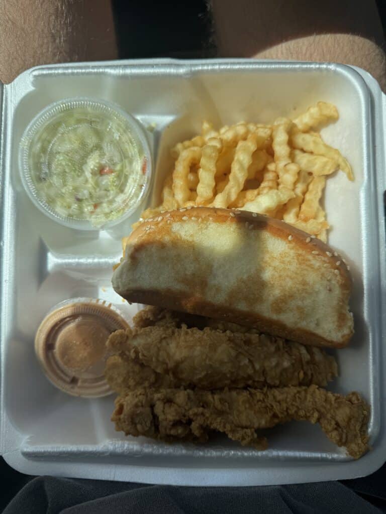 Box of food with fried chicken tenders, french fries, cole slaw, and sauce.