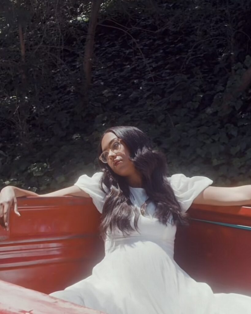 An image of Jensen Mcrae sitting in the back of a red truck, part of the artwork for her single 'Massachusetts'.