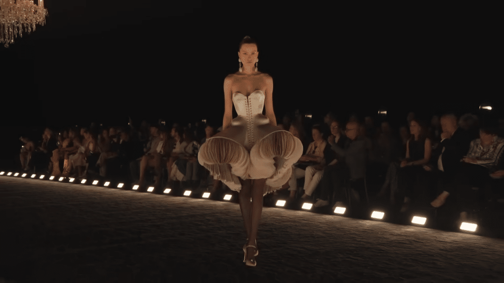 Runway model sporting a silver corset dress that has added movement from organza circles on the edges.