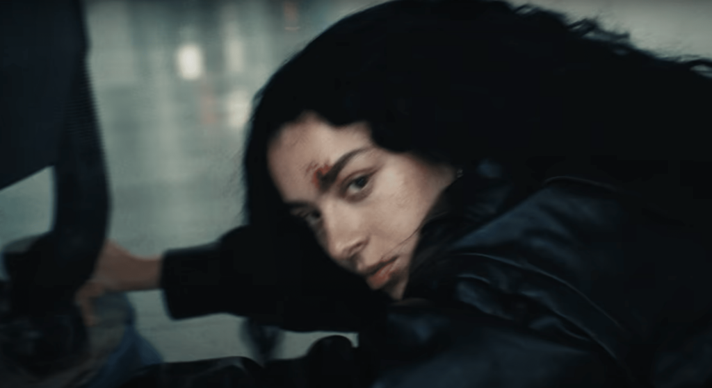 A screenshot of Charli Xcx looking into the camera in the music video for "Von Dutch".