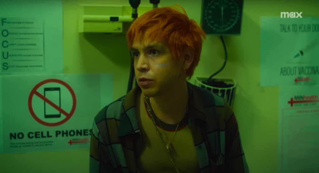 Julio Torres as Julio is sitting in a doctor's office with a sign that says 'No Cell Phones' behind him.