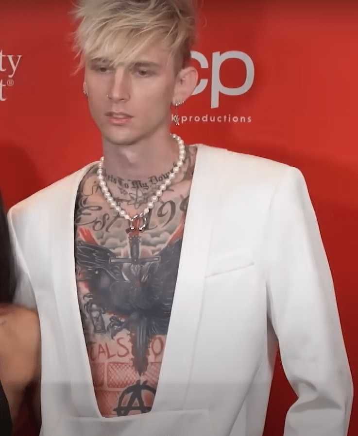 Machine Gun Kelly showing his chest tattoos.