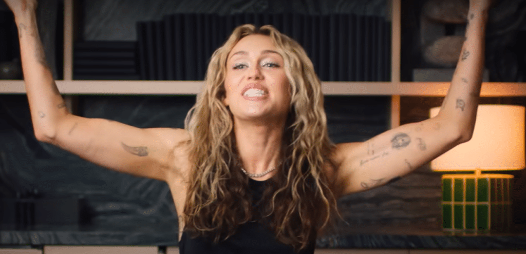 Miley Cyrus showing off multiple tattoos on her arms.