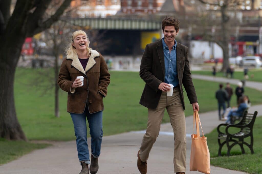 Florence Pugh and Adrew Garfield walking in a park acting as their respective characters.