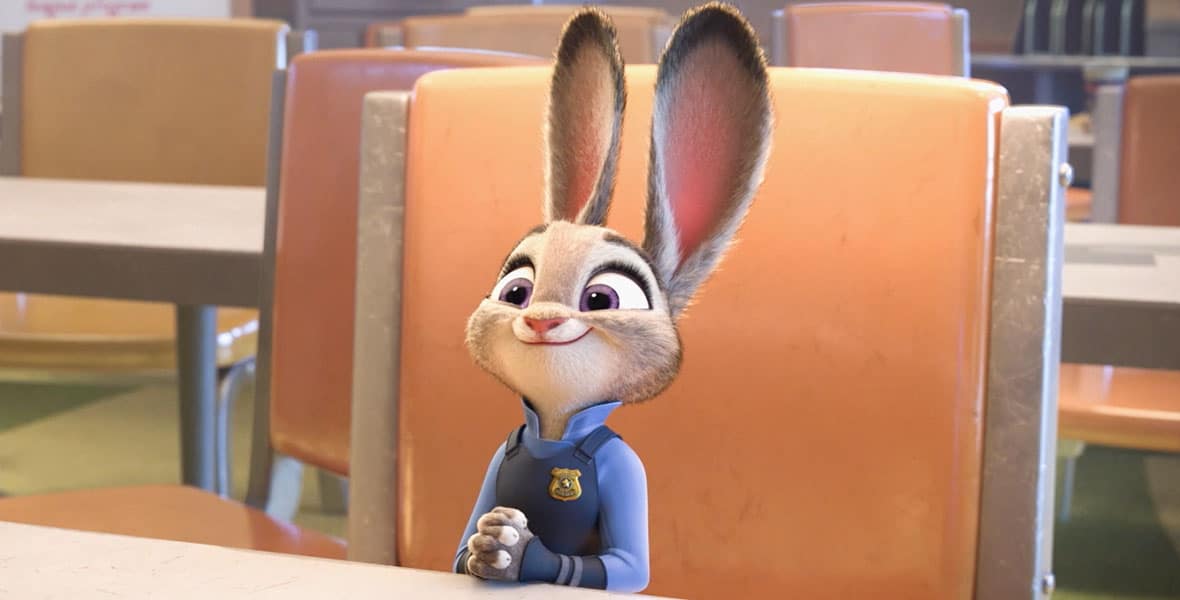 Smiling rabbit cop sits at a table with hands crossed.