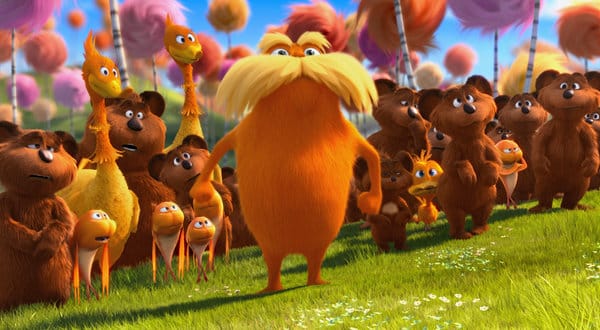 The Lorax stands before a group of yellow birds and brown bears.