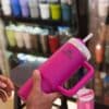 hands hold a pink Stanley tumbler in a store.