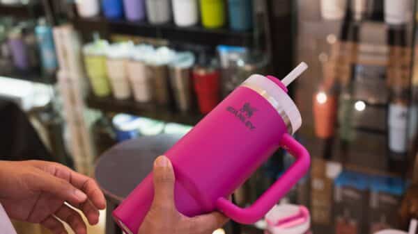 hands hold a pink Stanley tumbler in a store.