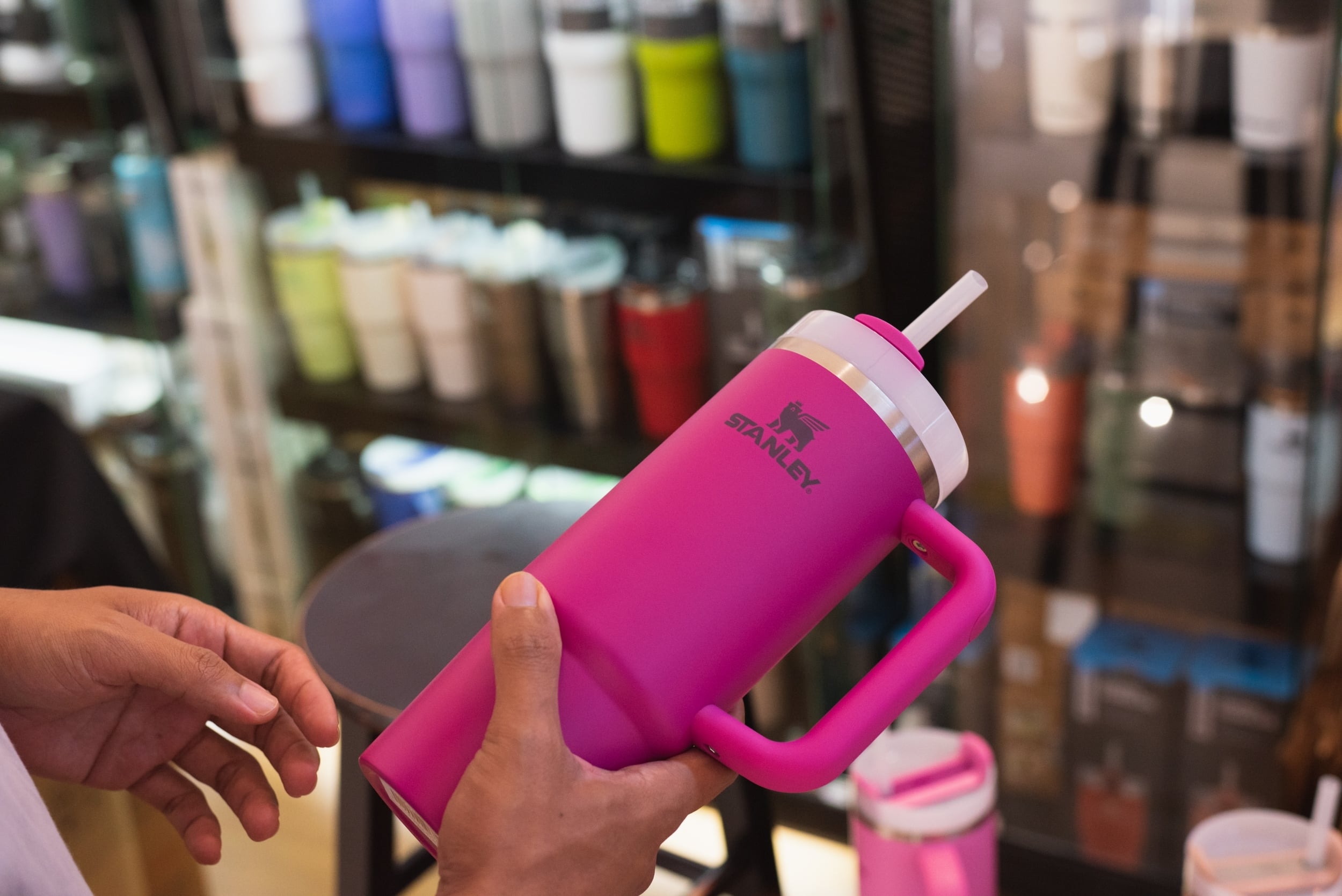 hands hold a pink Stanley tumbler in a store.
