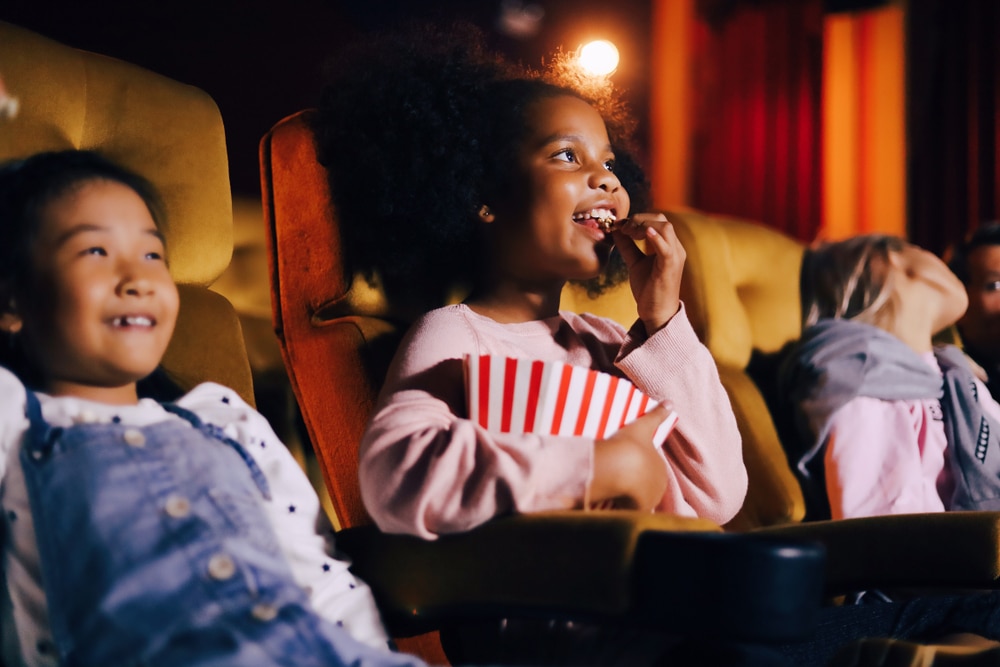 Little girl eating popcorn in a movie theater.