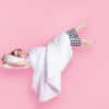 Graphic of a woman lying in bed in her pajamas on a pink background.