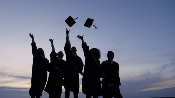 Silhouette,Of,Graduating,Students,Throwing,Caps,In,The,Air.