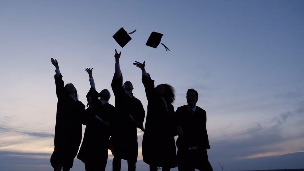 Silhouette,Of,Graduating,Students,Throwing,Caps,In,The,Air.