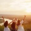Three girls toasting their drinks by the sunset