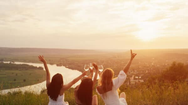 Three girls toasting their drinks by the sunset