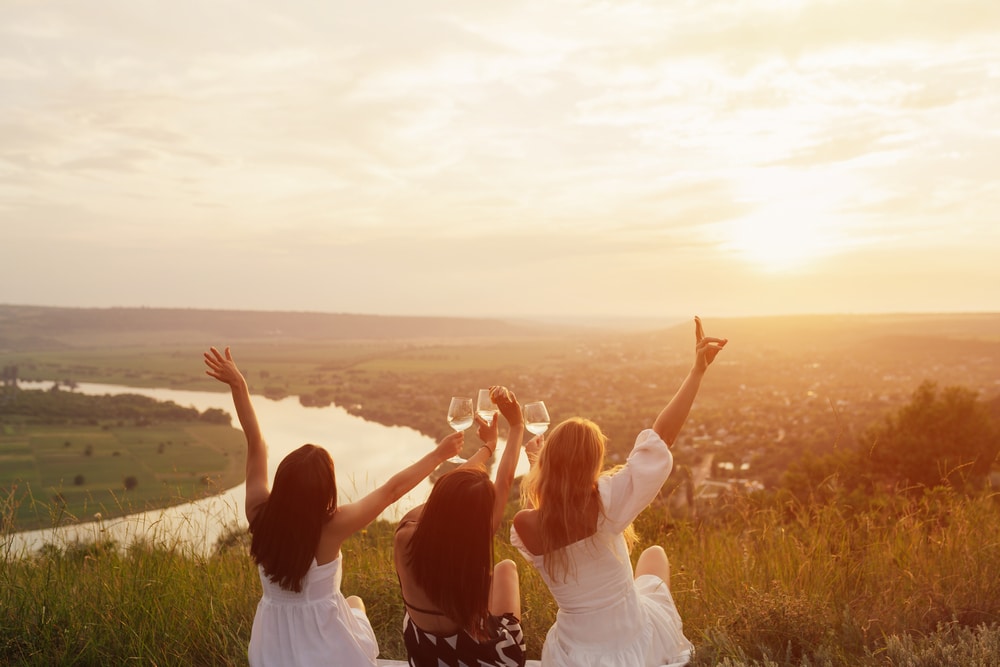 Three girls toasting their drinks by the sunset