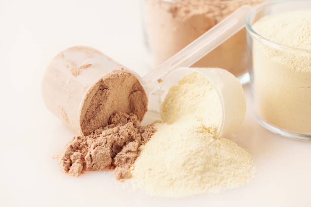 Scoops of white and brown protein powder on a white background.