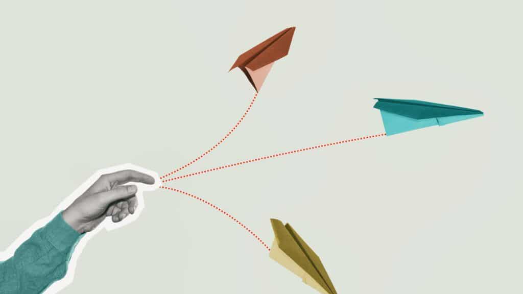 A realistic looking hand throws cartoon style paper airplanes against a blank background.