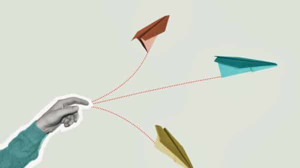 A realistic looking hand throws cartoon style paper airplanes against a blank background.