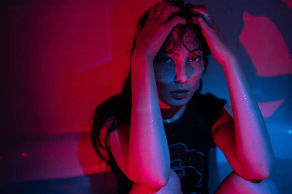 Portrait in red neon light of young depressed Asian woman