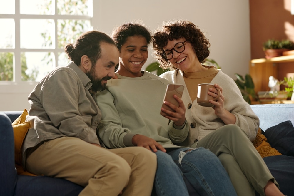 Mother, father, and daughter sitting on a couch and watching a video