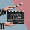 A pair of hands holding a clap board with 2024 written on it.