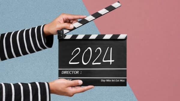 A pair of hands holding a clap board with 2024 written on it.