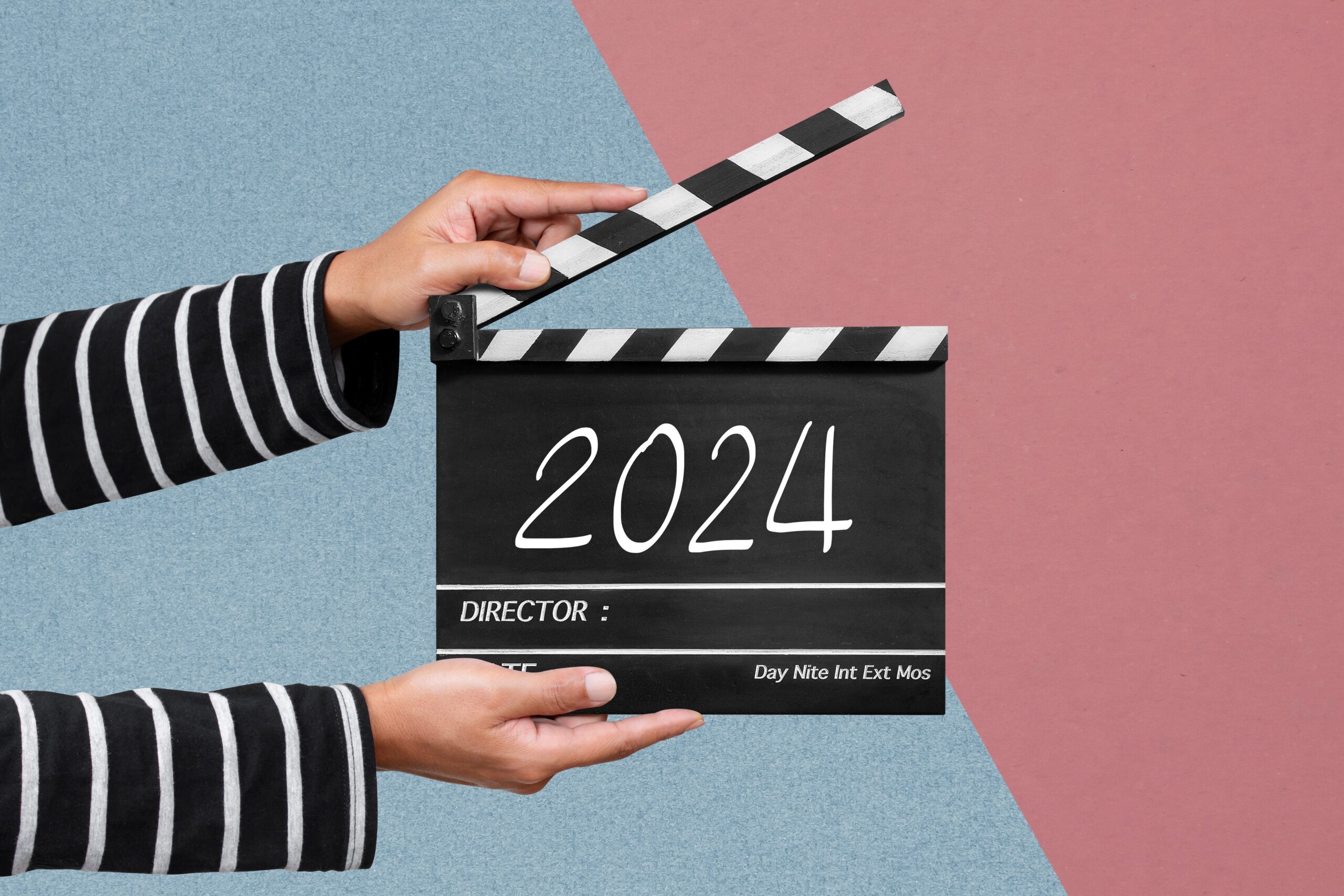A pair of hands holding a clap board with 2024 written on it.