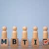 blocks with "mbti" lettering on a table with wooden people figurines