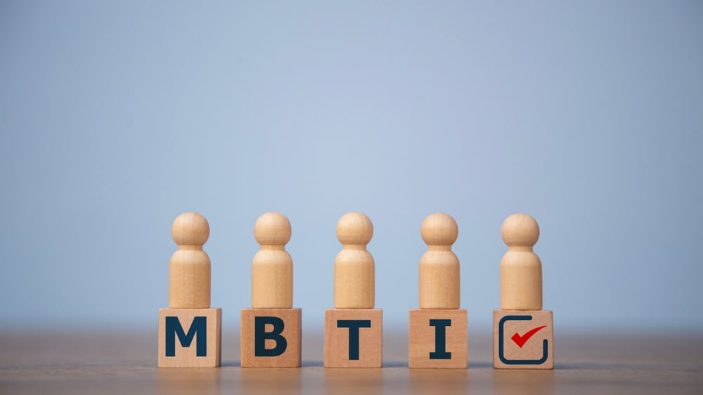 blocks with "mbti" lettering on a table with wooden people figurines